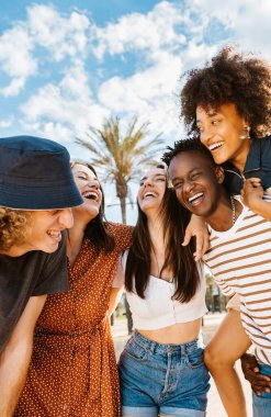 Bir grup çok ırklı mutlu genç arkadaş sahilde yaz tatilinin tadını çıkarırken Afrikalı çifte odaklanın.