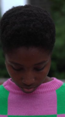 Dikey HD video. Genç siyahi kadın kafasını dışarı kaldırıyor ve kameraya gülümsüyor. Milenyum Afrikalı kısa saçlı trend bir kadının yakın plan portresi. Pozitif insanlar.