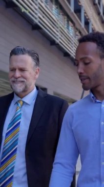 Üç başarılı iş adamının sohbetin tadını çıkarırken sokakta yürüdüğü dikey HD videolar. Ekip ortakları hareket halinde. Bina binasının dışında tartışıyorlar.. 