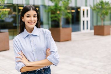 Şirket binasının önünde duran güçlü iş kadınının portresi. Liderlik ve güçlendirme kavramı.