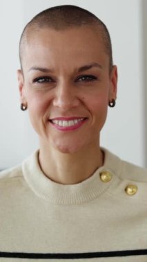 Dikey HD video. Evde dikilirken kameraya gülümseyen kafası tıraşlı yetişkin bir kadın. Mutlu insanlar konsepti, vesikalık, video çağrısı, POV web konferansı, webcam.