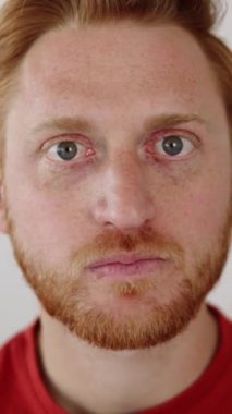 Neşeli genç adam komik suratlar yapıyor. Oyuncu kızıl saçlı adam izole edilmiş arka planda kameraya bakıyor.