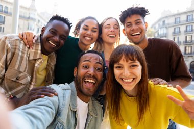Çeşitli genç ve mutlu arkadaşlar selfie çekerken eğleniyorlar. Uluslararası gençlik cemiyeti farklı insanların olduğu insanlar kendi portrelerinde kameraya gülümsüyorlar.