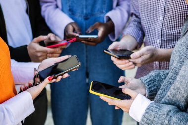 Dışarıda akıllı telefon kullanan tanınmayan bir grup genç öğrenci. Milenyum insanları ellerinde cep telefonu tutuyor