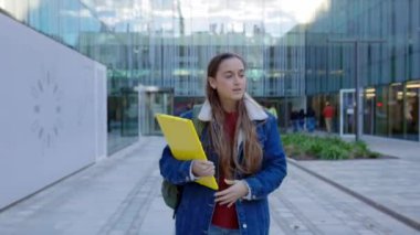 Dersten sonra kampüsten çıkarken cep telefonu kullanan beyaz bir kız. Eğitim ve teknoloji kavramı.