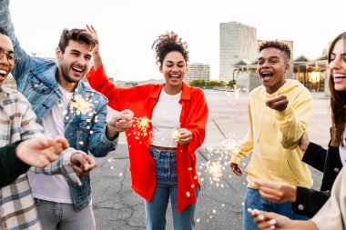 Genç ve mutlu bir grup insan partide birlikte eğleniyor. Farklı arkadaşlardan oluşan milenyum topluluğu festivalde dans ederek dışarıda parıltılarla kutlama yapıyorlar..