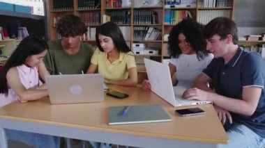 Kütüphanede dizüstü bilgisayarla çalışan bir grup genç öğrenci. Üniversitedeki grup ödevi projesinde çalışan çok ırklı üniversiteliler..