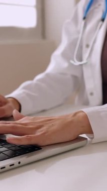 Tıp hastanesinde laptopta çalışan tanınmayan bir kadın doktorun dikey HD videosu.