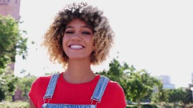 Kameraya gülümseyen Afrikalı Amerikalı genç bir kadının portresi. Binlerce yıllık Kolombiyalı bir kızın şehir sokağında durduğu vesikalık fotoğraf..