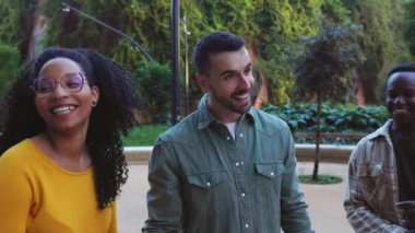 Milenyum insanlarından oluşan mutlu genç bir grup City Street 'te birlikte takılıyor. Gençlik toplumu ve çok ırklı kadın ve erkeklerin dışarıda konuşup eğlendiği arkadaşlık kavramı. Yavaş çekim görüntüleri. 