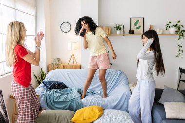 Evde pijama partisinde dans edip şarkı söyleyen üç mutlu genç kız. Kadın arkadaşlığı kavramı