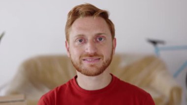 Yeni dairede otururken kameraya bakan mutlu kızıl adamın portresini yakın çekim. Mutlu insanlar, yeni hayat ve başlangıç konsepti