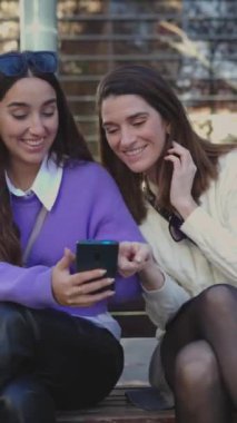 Akıllı telefon ekranından iyi haberler okuyan bin yıllık bayan arkadaşlarının dikey HD videosu. Cep telefonundan inanılmaz bir mesaj alan genç kadınlar.