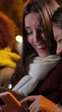 Milenyum arkadaşlarının cep telefonlarını açık havada yan yana otururken çektikleri dikey HD video. Şehir sokaklarındaki akıllı telefon cihazlarında sosyal medya içeriğini arayan çeşitli gençler.