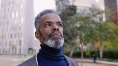 Şehrin dışında dikilen yaşlı Latin Amerikalı adamın portresi. Olgun bir erkeğin finans bölgesinde açık havada düşüncelere daldığı bir fotoğraf. İş insanları kavramı.