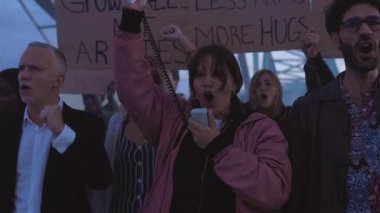 Genç kadın eylemci, savaş karşıtı posterler ve pankartlar taşıyan bir grup insanı izledi. Dünyada savaş ve şiddeti protesto eden bir gösteriye liderlik ettiler..