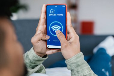 Akıllı telefonu evdeki kablosuz internete bağlayan genç adamın yakın görüntüsü. Teknoloji konsepti. Arka görünüm.