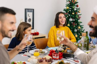 Mutlu aile Noel yemeğini evde yemek için masanın etrafında toplandı. Genç ve mutlu bir kadın Noel kutlamalarında hindi yerken komik deneyimler ya da hikayeler anlatıyor..