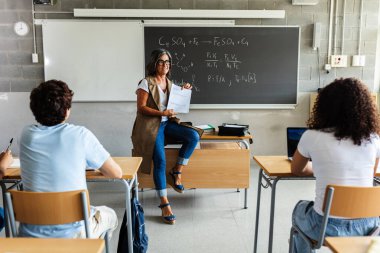 Genç nesil z öğrencileri lisede derse katılıyor. Genç siyah öğrenci ders sırasında kıdemli bayan öğretmene soru soruyor. Eğitim kavramı