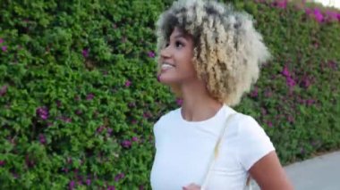 Şehir caddesinde yürüyen güzel, çok kültürlü bir kadın. Neşeli milenyum dişisi yazın açık havada yürüyüş yapıyor. İnsanlar ve mutluluk kavramı.