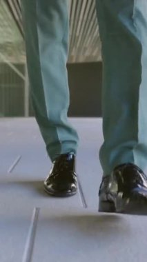 Modern inşaat bürosunda işe giderken iş adamlarının bacaklarını yakından izleyin. Dikey HD video.