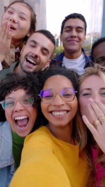 Çeşitli öğrenci gruplarının açık havada cep telefonu uygulaması kullanarak çevrimiçi video görüşmesi yaptıkları dikey POV videoları. Akıllı telefon sanal toplantı konferansında gülen ve eğlenen çok ırklı arkadaşlar.