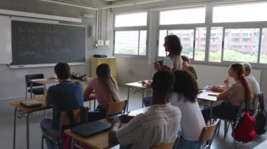 Üniversitede ya da okulda kıdemli yetişkin kadın öğretmenlik yapıyor. Bayan öğretmen sınıftaki öğrencilerine bir ders veriyor. Lise ve ortaöğretim
