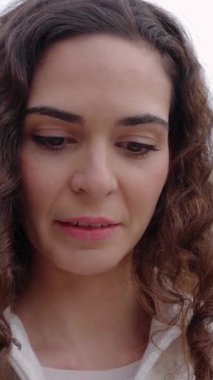 Şehir caddesinde cep telefonu kullanan mutlu bir kadının dikey HD videosu. Beyaz bir kadın cep telefonu uygulamasında sohbet ediyor, dışarıda sosyal medya içeriğini izliyor. Teknoloji ve şehir yaşam tarzı kavramı.