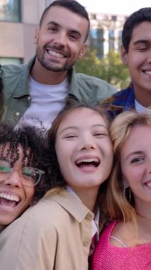 Dışarıdaki kameraya gülümseyen bir grup genç insanın dikey portresi. Mutlu milenyum kolej öğrencileri birlikte eğleniyor, gülüyor ve şehir sokaklarında takılıyor..