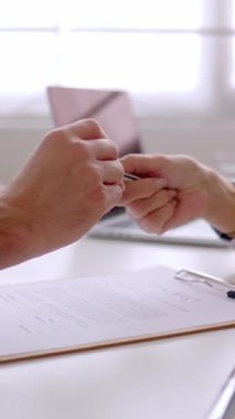 Dikey HD video. Genç çiftin ilk mülkü aldıktan sonra kalemle sözleşme imzalamasına yakından bakın. Profesyonel iş anlaşmasına başlayan iki işadamı. 
