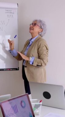 Profesyonel kıdemli iş kadınının dikey HD videosu yeni şirket projesi için fikirler sunuyor. İletişim, takım çalışması ve iş stratejisi kavramı