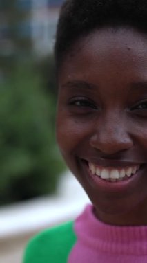 Dışarıda kameraya bakan gülümseyen Afrikalı genç bir kadının dikey HD videosu. Çeşitli mutlu insanlar konsepti