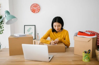 Genç girişimci Asyalı kadın müşteriye teslimat için paketler hazırlıyor. E-ticaret ve teslimat hizmeti kavramı.