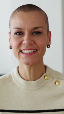 Dikey HD video. POV orta yaşlı kadın ev ofisinden çalışırken laptopta bir video görüşmesi yapıyor. Tıraşlı saçlı bir iş kadını iş arkadaşlarıyla internette konuşuyor. İş konsepti