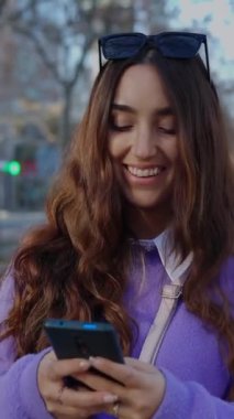 Şehir caddesinde cep telefonu kullanan trend bir genç kızın dikey videosu. Milenyum kız öğrencileri sosyal medya içeriğini kentsel arka plandan izliyorlar. Cep telefonuyla konuşan bir kadın.