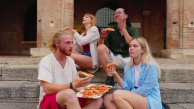 Şehir caddesinde pizza yiyen gençler. Milenyum gençleri, İtalya 'da yaz tatilinin tadını çıkarırken birlikte pizza yiyorlar.. 