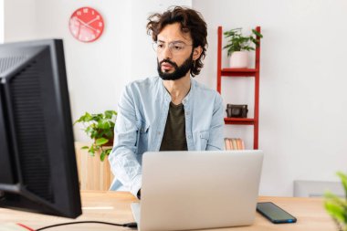 Genç yaratıcı adam evdeki masaüstü bilgisayarında çalışıyor. Dijital tasarımcı ve girişimci insan konsepti.