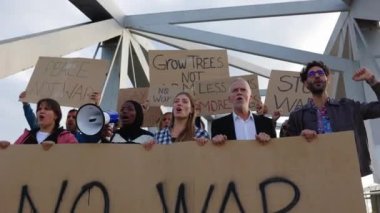 Dünyada savaş ve şiddeti protesto eden çeşitli aktivist grupları posterler ve pankartlar taşıyorlar..