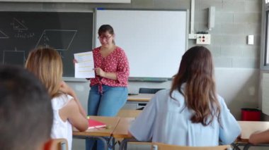 Genç ilkokul öğretmeni okuldaki öğrencilerine egzersizleri anlatıyor. Sınıfta okuyan 10 yaşında öğrenciler. İlkokul ve eğitim konsepti.
