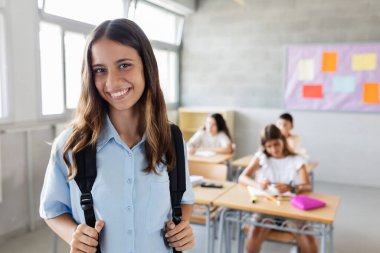 Sınıfta sırt çantalı gülümseyen ilkokul öğrencisi kız. Eğitim kavramı