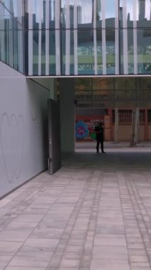 Dikey video: genç başarılı iş kadını çalışma saatinin sonunda cep telefonu kullanırken ofisten çıkıyor.