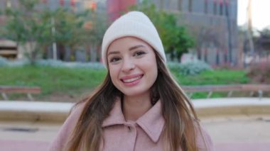 Şehir caddesinde kameraya gülümseyen kışlık elbiseli güzel bir kadın. Dışarıda beyaz tenli çekici bir kızın portresi var. Gençlik kavramı.