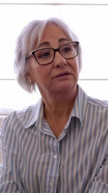 Dikey video. Toplum merkezinde birbirini destekleyen terapi grubu üyeleri. Profesyonel rehberlik toplantısında depresyondaki kıdemli kadın ortağı sakinleştiren gençler. 