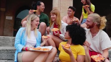 Genç neşeli çok ırklı arkadaşlar sokakta pizza yiyorlar, İtalya 'da yaz tatilinin tadını çıkarıyorlar. İtalyan halkı, gençlik topluluğu ve seyahat tatilleri konsepti.