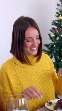 Genç yetişkin bir çiftin aile Noel yemeğinde önemli bir duyuru yaptığı dikey HD video. Akşam yemeğinde heyecan verici iyi haberleri kutlayan bir grup insan: hamilelik ya da düğün.