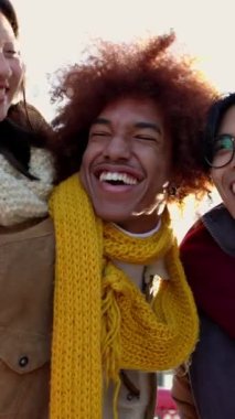 Genç mutlu arkadaş grubunun kış günü selfie çekerken çekilmiş dikey HD videosu. Milenyum insanları sıcak kıyafetler giyip seyahatin tadını çıkarıyorlar.