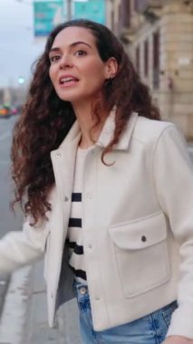 Barcelona 'da taksi arayan seyahat valizli güzel bir kadının dikey HD videosu. Seyahat ve özel ulaşım kavramı.