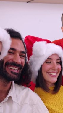 Noel kutlamalarında kanepede yan yana oturan üç nesildir gülümseyen bir ailenin dikey HD videosu. Büyükbaba, anne, baba, oğul, kız ve torunlar fotoğraf için poz veriyor..