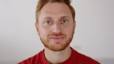 Kapalı alanda kameraya gülümseyen neşeli kızıl saçlı adamın yakın portresi. Mutluluk ve pozitif insanlar kavramı