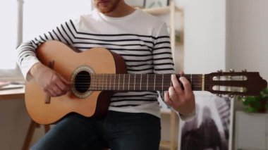 Evinde gitar çalan tanınmayan bir delikanlının yakın çekimi. Boş zaman ve hobiler konsepti